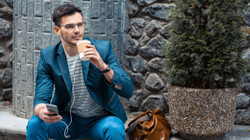 Young man sitting outdoors holding a mobile device and drinking coffee, for Raleigh financial 
planning from Hunt Insurance.