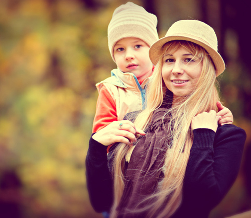 Outdoor photo of a young blonde woman with her young son on her back; for information on Raleigh-Durham term life insurance from John Hunt Insurance.