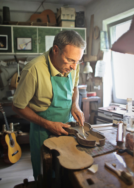 Self-employed wooden instrument maker carving a violin; for information on Raleigh disability income insurance from Hunt Insurance.