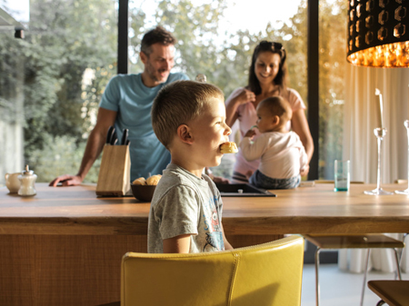 Dad, mom, and two kids in the kitchen with the son in the forefront eating a biscuit; for information on North Carolina life insurance from John Hunt of Raleigh.