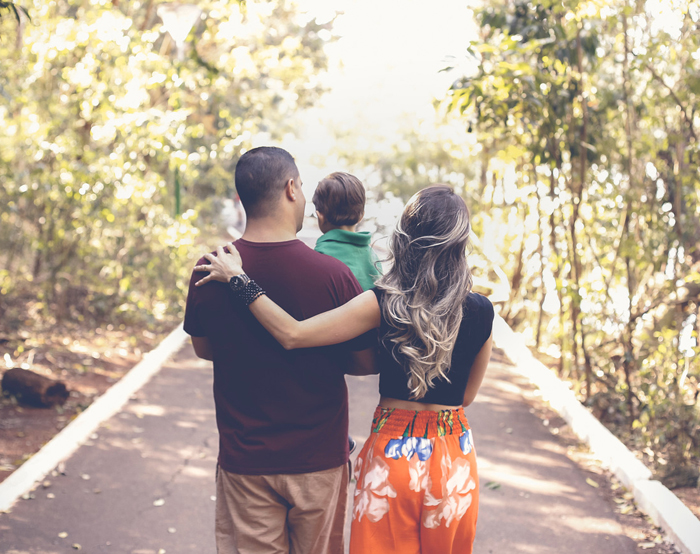 Dad holding toddler and walking with mom on a park pathway, or info on how much life insurance you need in Raleigh, NC