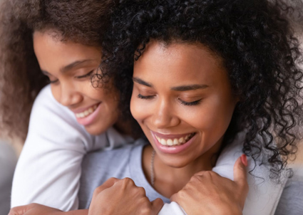 Head-and-shoulders scene of African American mom and daughter hugging